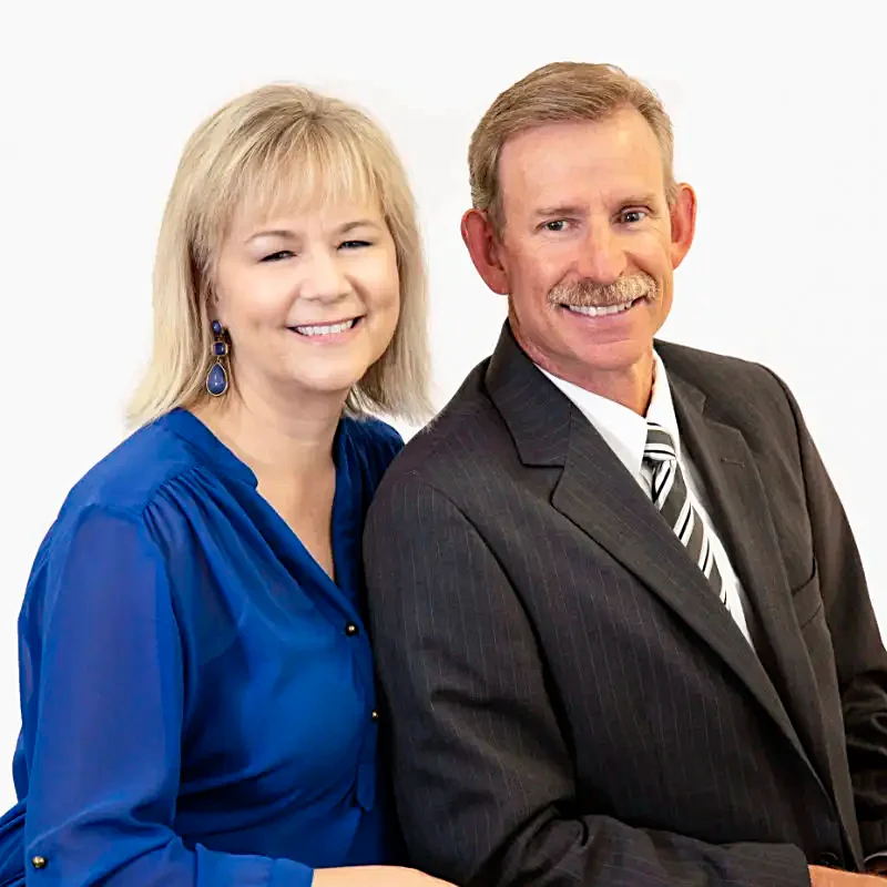 Mortgage company founders Chris and Linda Love smile for a portrait. Linda wears a blue blouse; Chris wears a suit and tie.