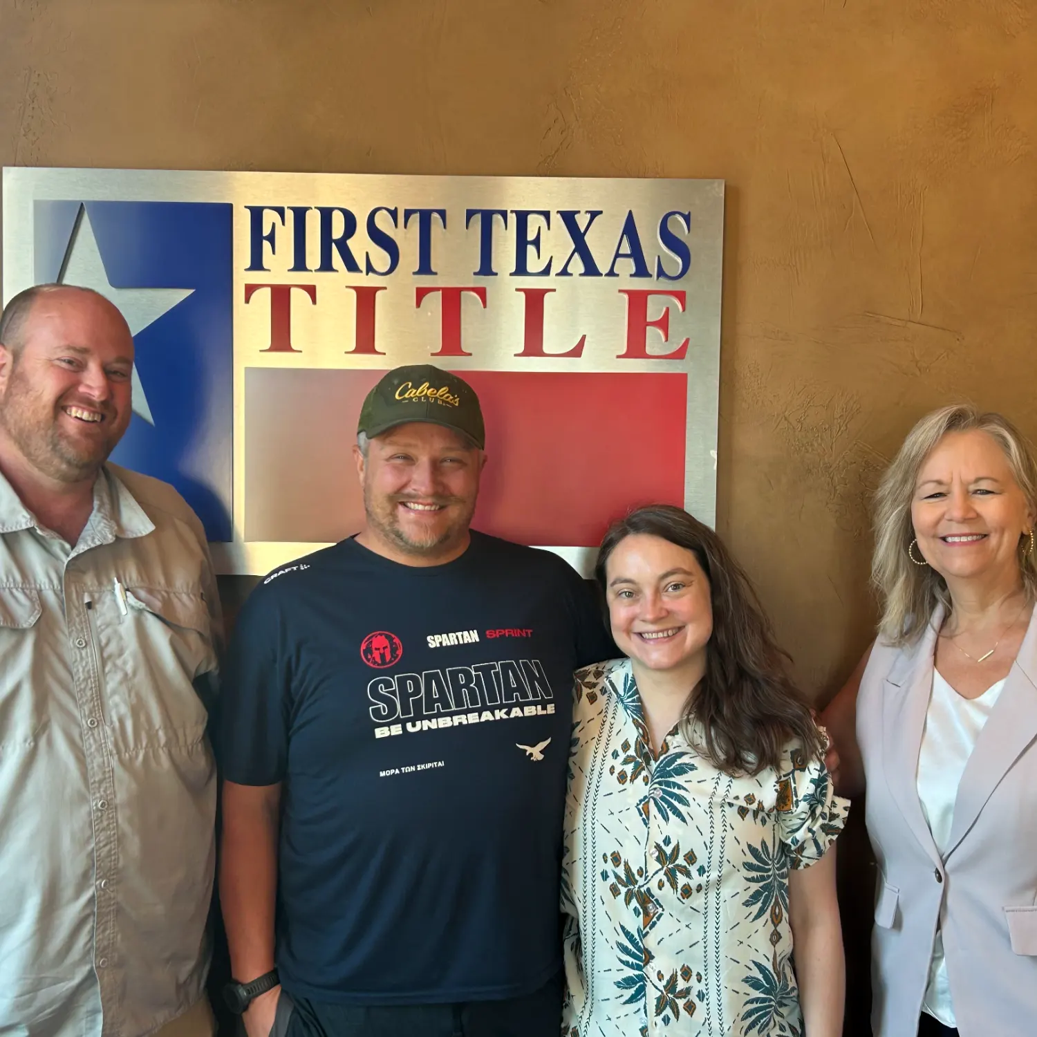 Four people, including mortgage broker Linda Love and a smiling couple, pose happily in front of the First Texas Title sign after a successful closing.