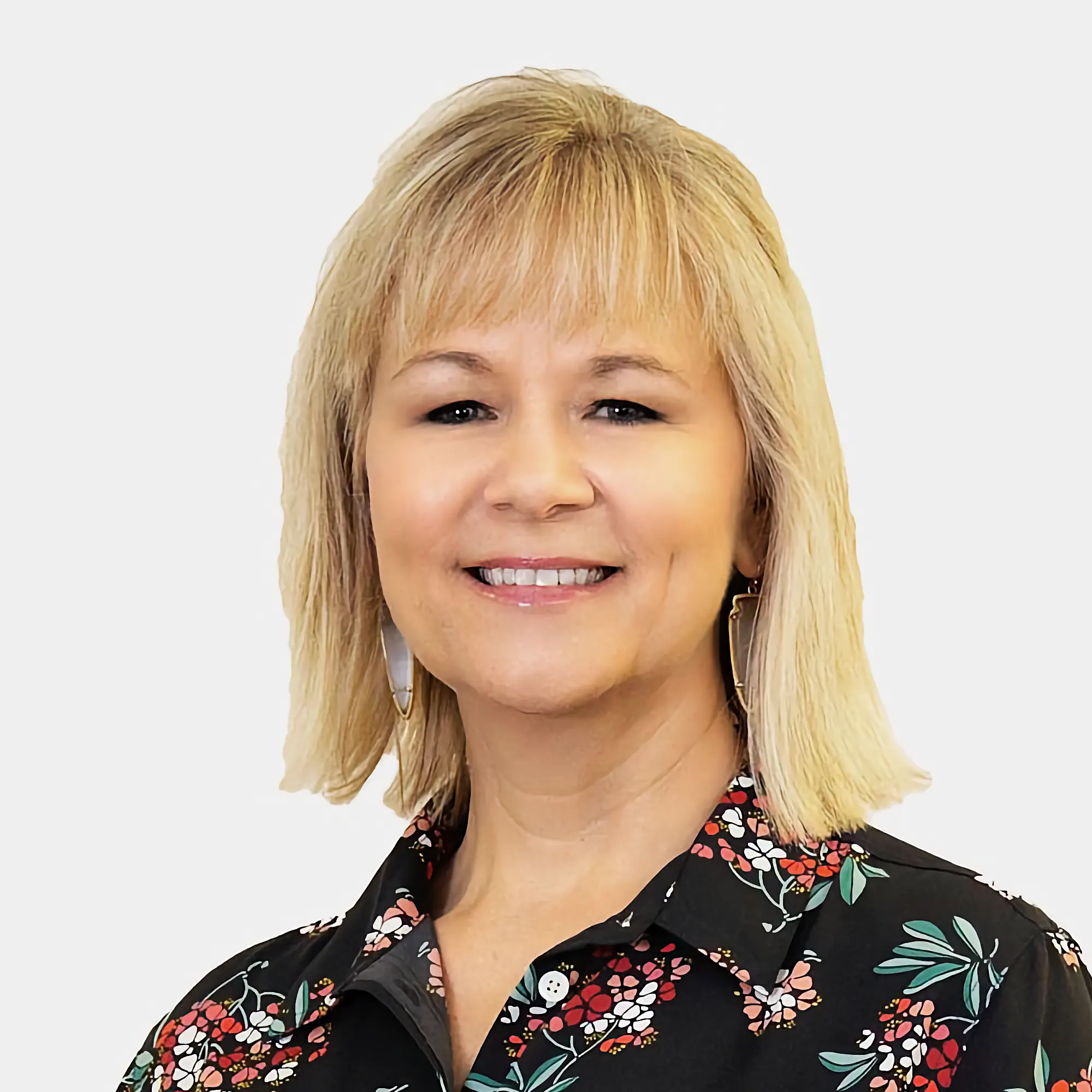 Linda Love, Residential Mortgage Loan Originator, smiles confidently. She has blonde hair and wears a black floral blouse and distinctive geometric earrings.